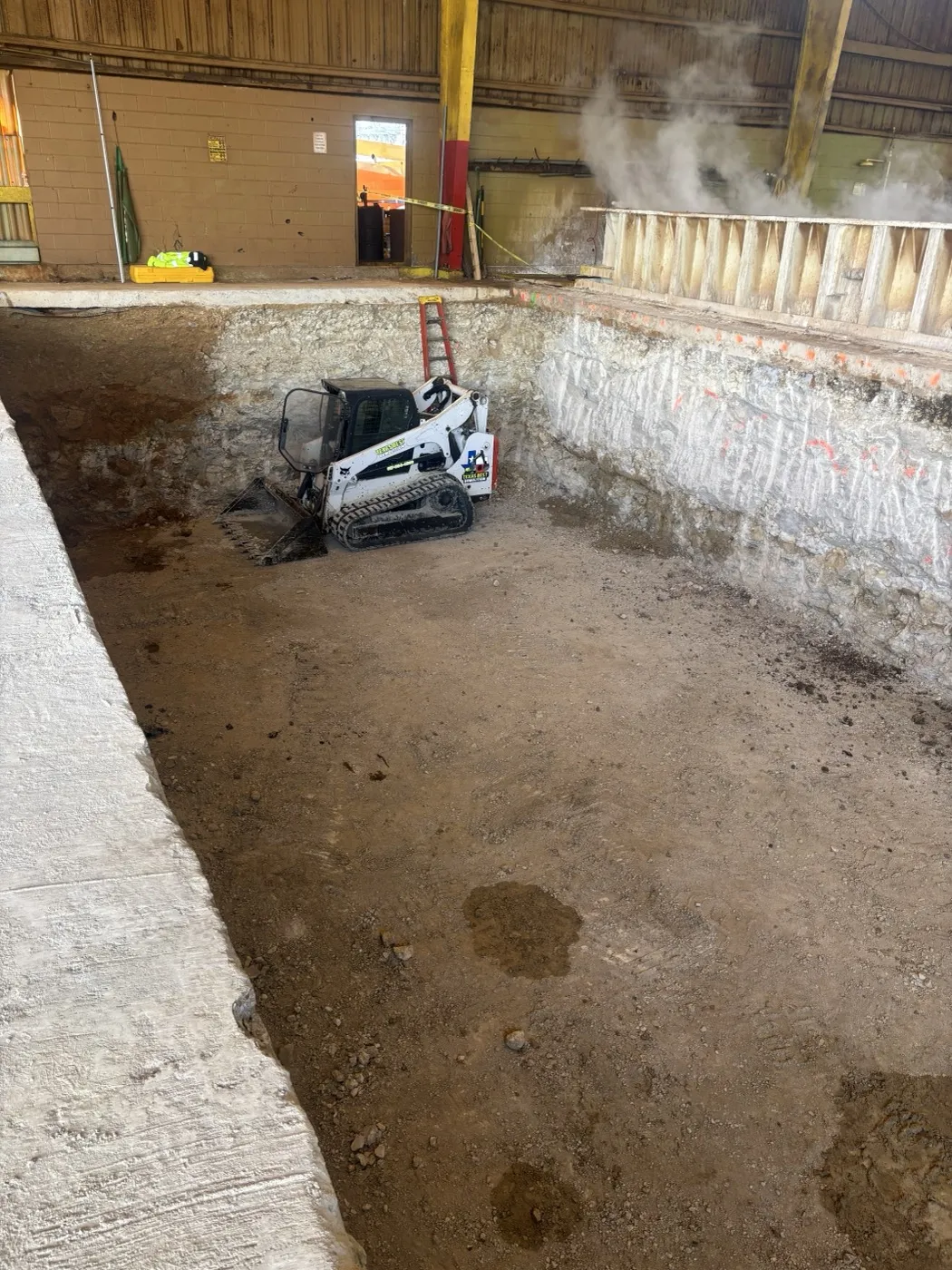Skid steer working the floor of an interior demolition pit