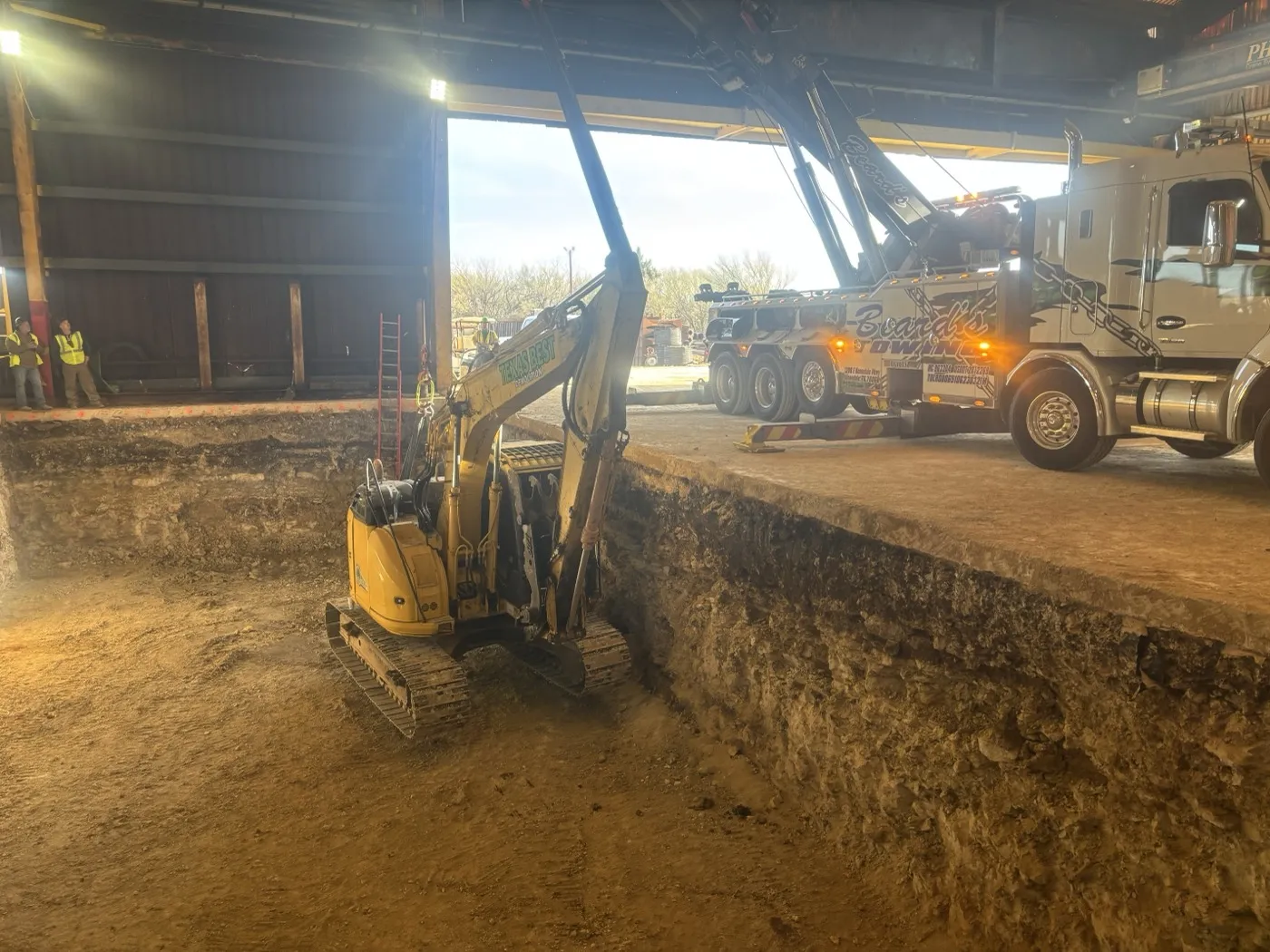 Compact excavator working below floor level inside a commercial building